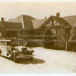Front view of Mount Dandenong Hotel with Blue Dandenongs Service car in foreground. Travellers booked a seat for door to door service to the city. The hotel opened in 1935. The Olinda Garage was built by Sam Patterson to service 'Service Cars' but had no petrol.