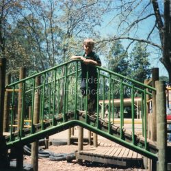 Miss Bell (1900 1984) The Miss Bell Playground was named after Miss Rebecca Adelaide Bell, a retired teacher who regularly helped out at Mount Dandenong Primary school for 8 years. Born in NSW, Miss Bell had taught in several states and had fond memories of holidays spent at Mountjoy in the Dandenong Ranges. When she retired Miss Bell built a home in Jeeves Avenue where she lived out the rest of her life with her Siamese cats. Miss Bell helped the children with reading, grammar spelling and history. She really cared about the children and her school visits brought her a lot of happiness.: Student standing on section of play equipment in Miss Bell Playground 1997.