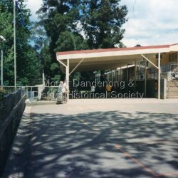 The first Mount Dandenong State School opened in a shed on the property of William Ferguson on the corner of Blythe and Old Coach Roads. The first teacher was Miss Ethel Gruber who opened the school on May 11th, 1897. It wasnt until 1901 that the school shifted over the road into an old school building that was moved up to the new site from Ringwood. All the buildings were demolished to make way for a new school that opened in 1991.: Looking across from asphalted area to the 'undercover area' November 1997.