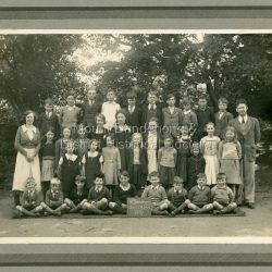 Formal school photograph showing staff and students of Mt Dandenong State School No. 3284 taken in 1937. Mounted on stiff cardboard.: Handwritten on rear of photograph: Betty Jeeves (Law Smith) 3rd from right second front row. Ken Jeeves 1st left, back row. Stamped on back G.E.HAINS Photographer 61 HARCOURT ST. HAWTHORN EAST, E3 1/6