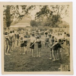 Pupils from Mount Dandenong State School wearing bathing costumes and exercising on the grass at Lilydale Pool 1938.: On back of photograph: Mount Dandenong Pupils at Lilydale Baths 1938?