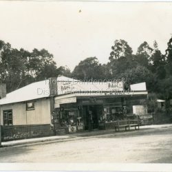 Small photograph showing E.M. Gill's Store in Main Street Olinda. As well as a general Store and Newsagency it served as the booking office for US Motors. Gill's Place handwritten on back of photograph.