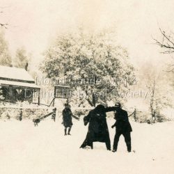 Three people playing in snow outside the Mission Hall in the Main Street of Olinda. Current Mangana Store covers this site.: On back of photograph - Mission hall OLINDA. Mission Hall Olinda in the snow.