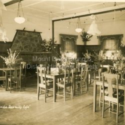 View of interior of Quamby Café set up for a function with hanging decorations and flower arrangements.: On front - "Olinda Quamby Café" On Back - Lilly Dingley