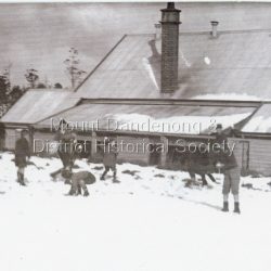 Outdoor scene at Olinda State School Number 3494 showing a group of school children throwing snowballs. The school was opened in 1906. This photo was taken mid 1920s.