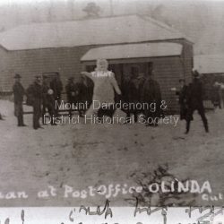Group of people building a very large snowman outside the Olinda Post Office and Wine Hall. The Wine Hall was built by Joseph Gutmann in 1900 and the Post Office opened in 1901. Photo is from c1920s.