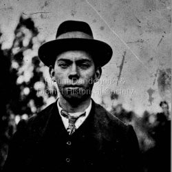 Jim Woolrich, brother of Ted and son of George Woolrich dressed in a suit, tie and hat. In 1917 Jim started a passenger car service from Ferntree Gully to Olinda with his father, George. This did not last long. Around 1919 Jim had started a nursery on part of his father's land in Olinda. He produced and sold flowers and foliage to shops.: Jim Woolrich