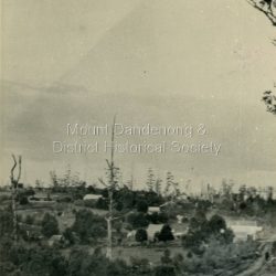 1909 view of Olinda showing 'Charlemont' guest house and the Olinda school on the skyline above Dodd's stables. Range Road (The Bullock Track) is in the foreground. The descriptive text on the reverse of this photograph was hand written by John Lundy-Clarke.: 1909 view of Olinda from Range Road (The Bullock Track). Showing school on skyline above Dodds stables with Charlemont on left.