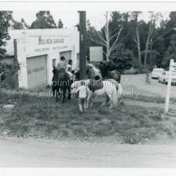 Olinda garage on corner of Range Road and Mt Dandenong Tourist Road. Pony Club with 4 horses on grass. Ralph Jones was garage owner at this time. Dragster bike on road indicates early 1960s.