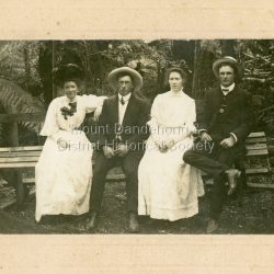 Formal photograph of Mary Dorey with three friends seated on a bench in a bush setting. All are well dressed. L to R Anita Grosman, H Dunn, Mary Dorey, Fred Webb. c1909: Handwritten on back: Anita Grosman, H Dunn, Mary Dorey, Fred Webb. Taken about 1909.
