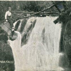 Original post card showing young man sitting on rock at the top of the Falls, LHS. Caption on front is Upper Olinda Falls but in Erasmus B Allen's tourist guide of 1904, these falls are described as Olinda Falls 2nd Leap.
Writing on back of postcard identifies the young man as Fred Dorey, brother of Iris Woolrich nee Dorey and the date as between 1897 and 1905.: Handwritten on back of card in blue pen: Fred Dorey at Olinda Falls (after 1897 before 1905) Printed on front of card: Upper Olinda Falls