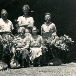 Iris and Ted Woolrich pose with a group at Range View Nursery in the 1950s. Bagged rhododendrons at the front. L to R: John Jaggers, Henk Koelwyn, Ted Woolrich, Iris Woolrich & Alice.: Handwritten on the reverse in pencil: John Jaggers, Henk, Ted, Alice & Iris