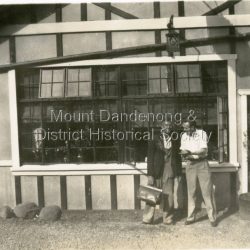 Close up photograph of the front of Quamby Café with two men standing, chatting. One man is holding a Gladstone bag. c1950s Close up photograph of the front of Quamby Café with two men standing, chatting. One man is holding a Gladstone bag. c1950s