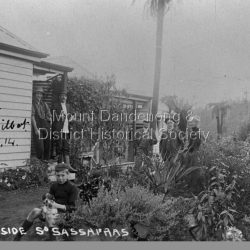 Group of people outside Sunnyside building at South Sassafras (now Kallista).
L to R: Frank Roberts, R H Croll, C. Web Gilbert, J G Roberts, Roberta Roberts.
Front is Bert Roberts with dog.
Marked on the front: To Mrs. Roberts, C. Web Gilbert 1.5.14
Sunnyside South Sassafras. G.G.M. Photo