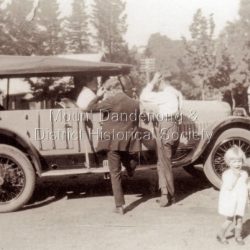 Two men looking closely at a car in Main Street of Sassafras. Probably during the visit of Edward, Prince of Wales in 1920.: Copy of a black and white photo showing two men and two children standing near a car. The men looking at the car, the children looking t the ca,era.